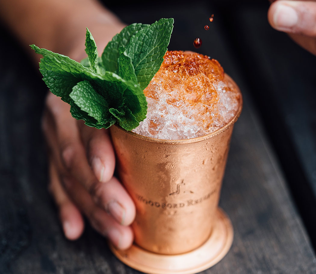 Closeup of a bartender's hand holding a copper cup, filled with an alcoholic beverage. Stock image taken by Adam Jaime.